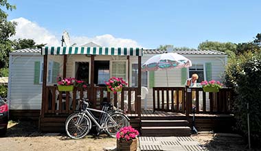 Fahren Sie vor der überdachten Terrasse eines Mobilheims, das Sie auf dem Campingplatz in Saint-Hilaire-de-Riez mieten können