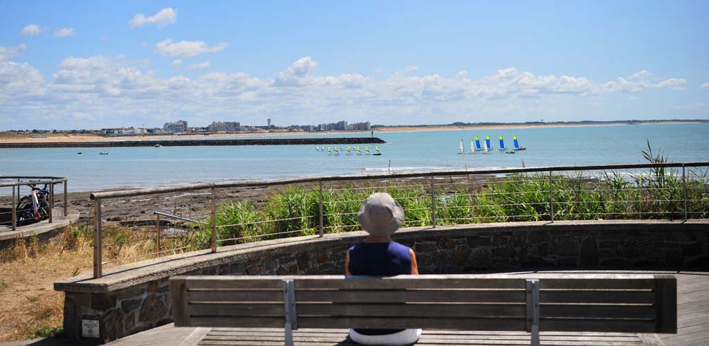 Frau, die auf einer Bank vor dem Meer auf dem Gesims von Saint-Hilaire-de-Riez sitzt