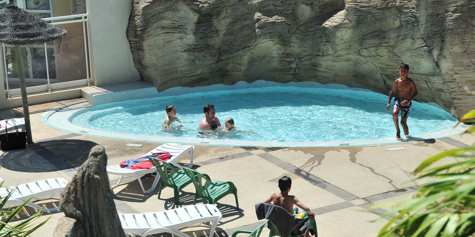 Paddling pool and pool area with deckchairs at Le Bois Tordu 85 campsite