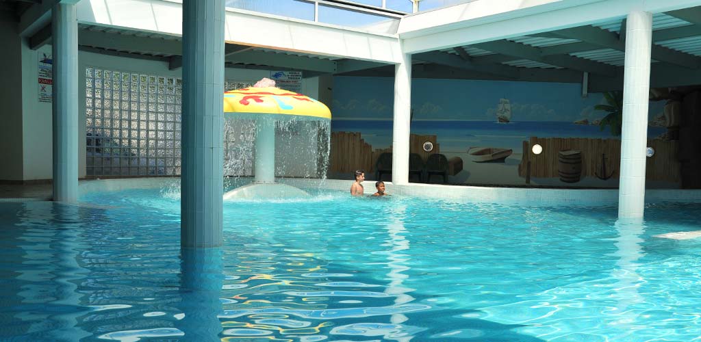 Indoor pool with fountain and water jets at Le Bois Tordu campsite in Saint-Hilaire-de-Riez